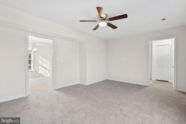 carpeted spare room with ceiling fan with notable chandelier