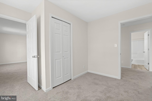 unfurnished bedroom featuring a closet and light colored carpet