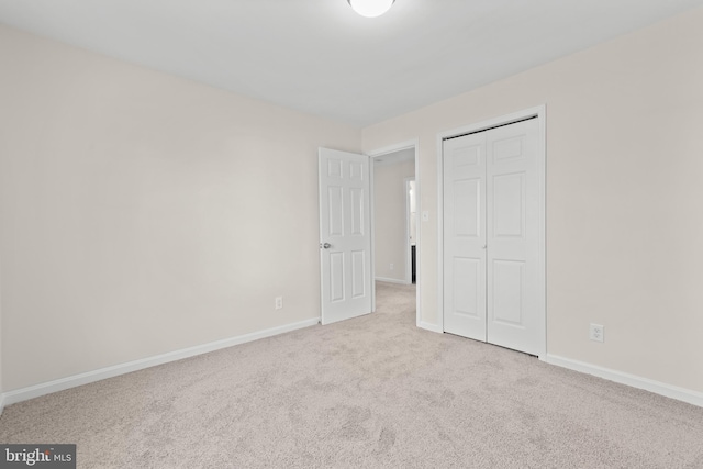 unfurnished bedroom featuring light carpet and a closet