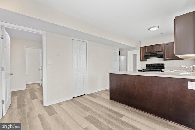 kitchen with kitchen peninsula, dark brown cabinetry, sink, black range, and white fridge