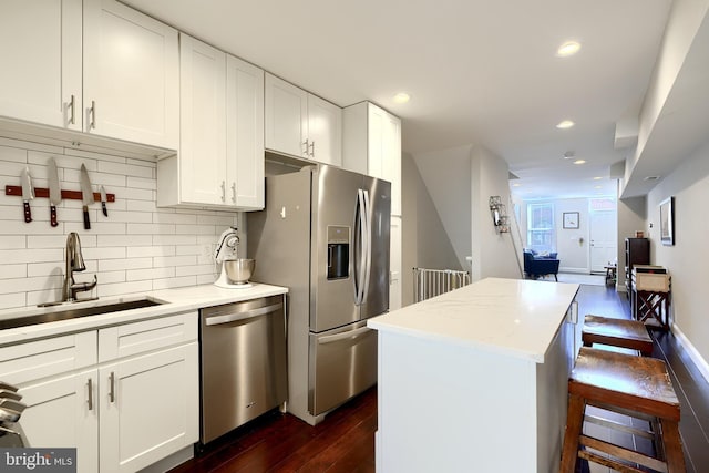 kitchen with a center island, stainless steel appliances, white cabinetry, and sink