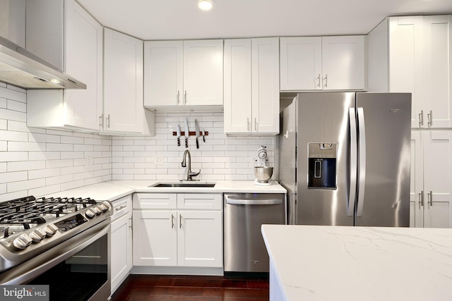 kitchen with wall chimney exhaust hood, white cabinetry, sink, and appliances with stainless steel finishes