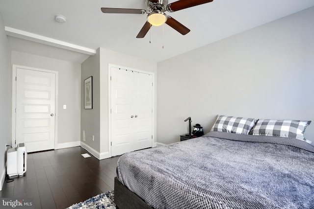 bedroom with ceiling fan, dark wood-type flooring, and a closet