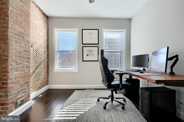 office space with dark hardwood / wood-style floors, brick wall, and a wealth of natural light