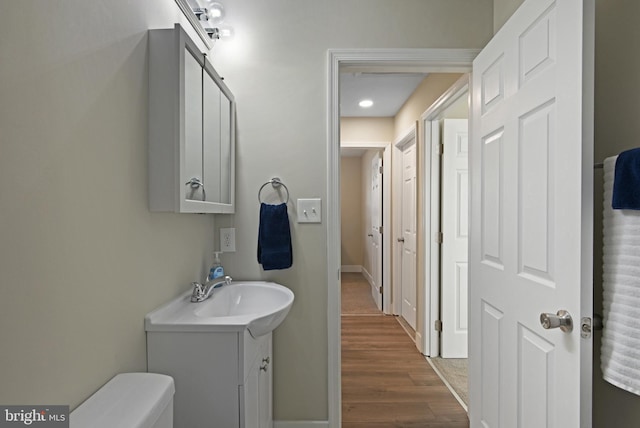 bathroom with wood-type flooring, vanity, and toilet