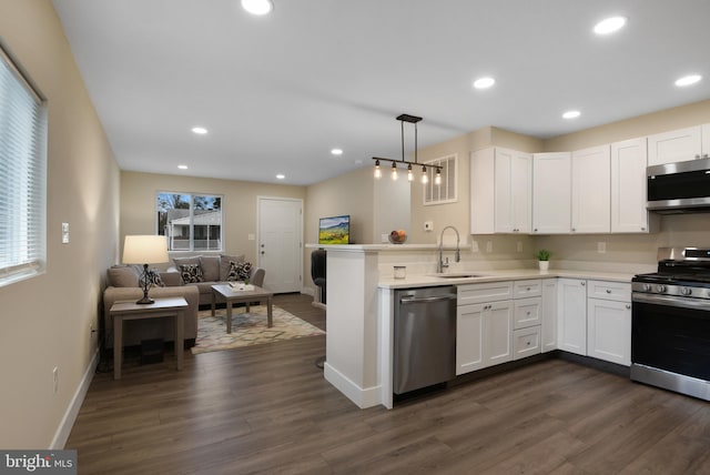 kitchen featuring sink, hanging light fixtures, stainless steel appliances, kitchen peninsula, and white cabinets