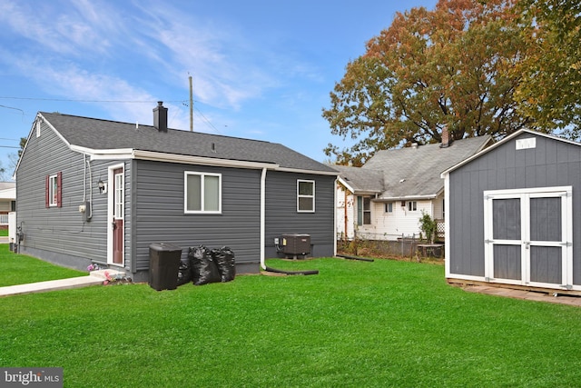 back of property featuring a lawn, cooling unit, and a storage shed