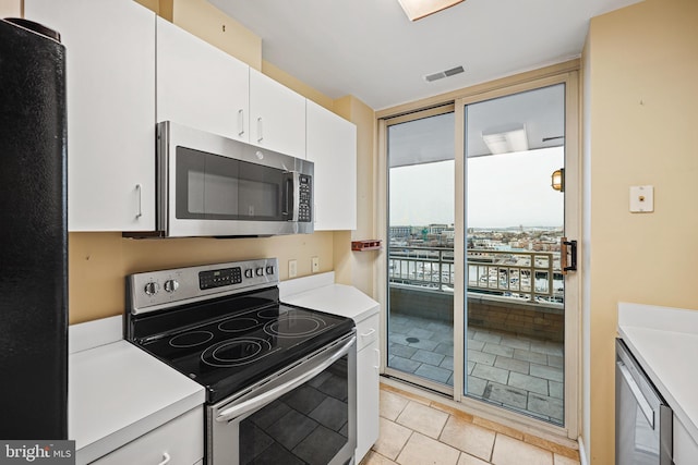 kitchen featuring light tile patterned floors, stainless steel appliances, white cabinetry, and beverage cooler