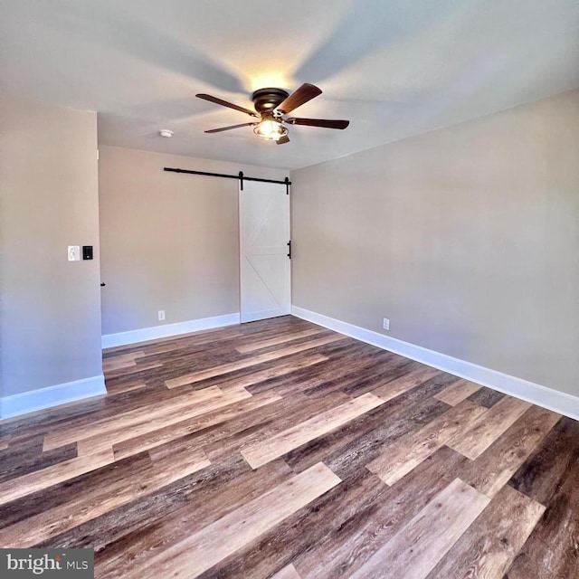 empty room with hardwood / wood-style floors, a barn door, and ceiling fan