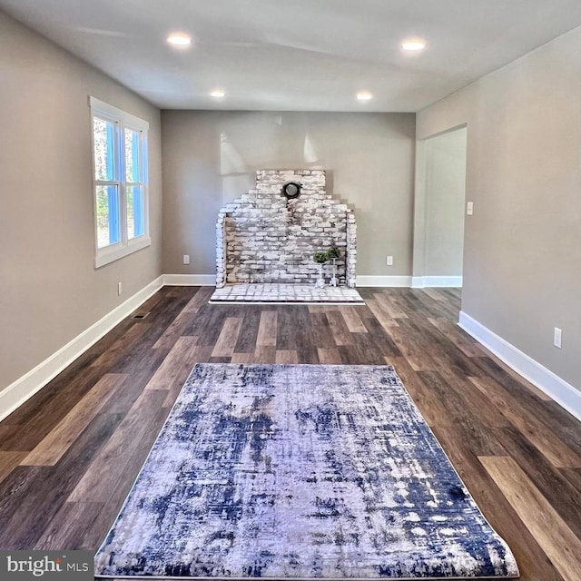 interior space with a stone fireplace and dark hardwood / wood-style flooring