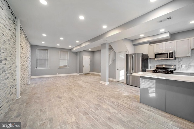 kitchen featuring gray cabinets, light hardwood / wood-style floors, appliances with stainless steel finishes, and tasteful backsplash