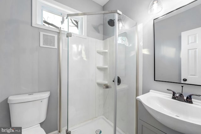 bathroom featuring a shower with door, vanity, and toilet