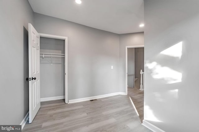 unfurnished bedroom with light hardwood / wood-style flooring and a closet