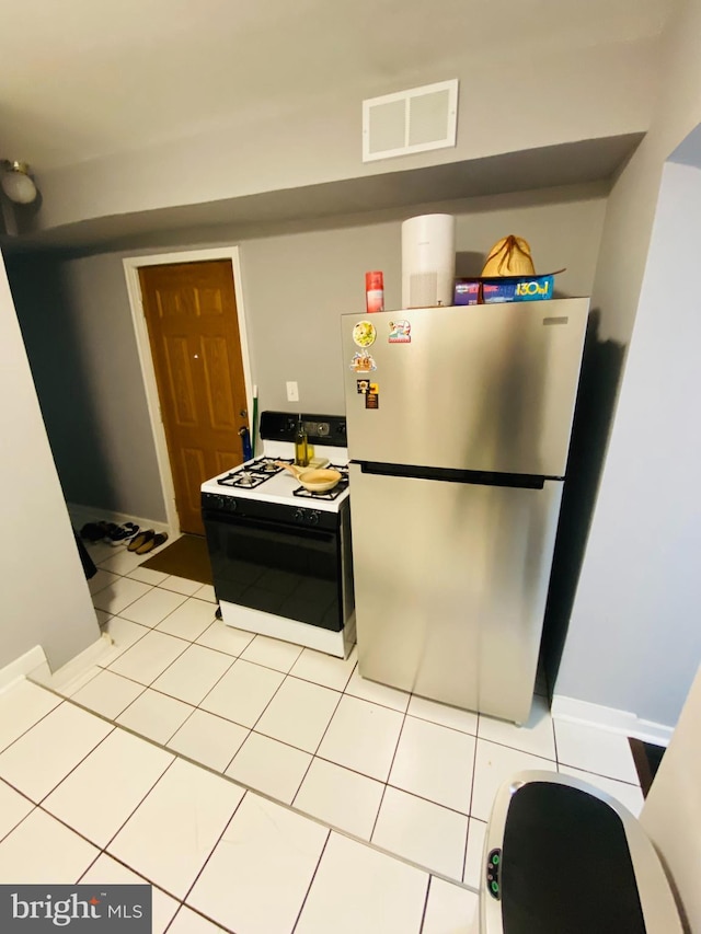 kitchen featuring range, light tile patterned flooring, and stainless steel refrigerator