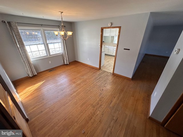 unfurnished dining area featuring wood-type flooring and a chandelier