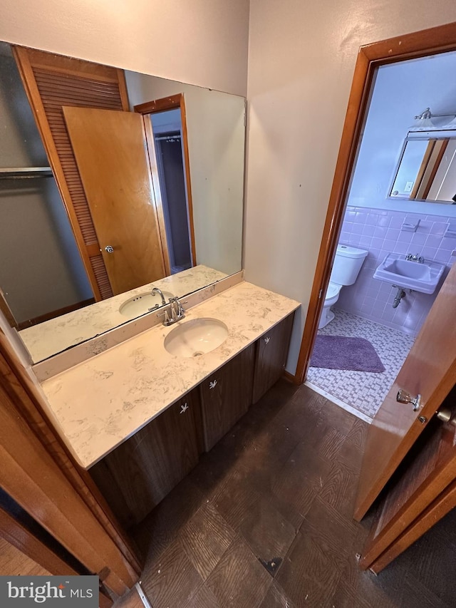 bathroom featuring toilet, tile walls, and sink