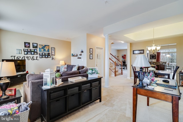 carpeted living room with an inviting chandelier, a raised ceiling, and decorative columns