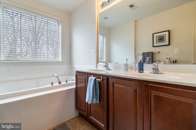 bathroom with vanity, a relaxing tiled tub, and tile patterned floors