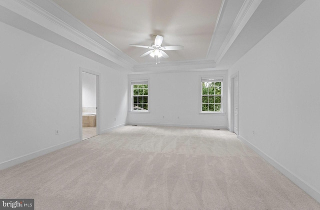 spare room with ornamental molding, a tray ceiling, ceiling fan, and light colored carpet