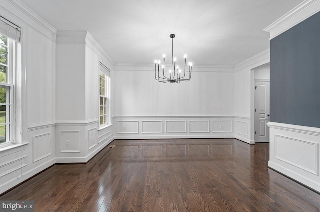 unfurnished dining area featuring dark wood-type flooring, crown molding, and a chandelier