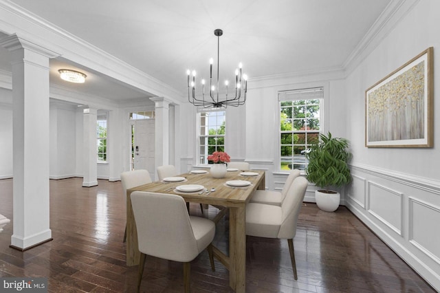 dining area featuring dark hardwood / wood-style floors, crown molding, a notable chandelier, and ornate columns