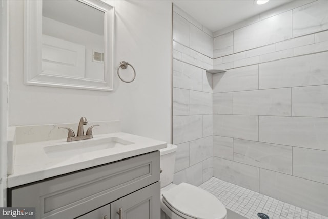 bathroom featuring tiled shower, vanity, and toilet