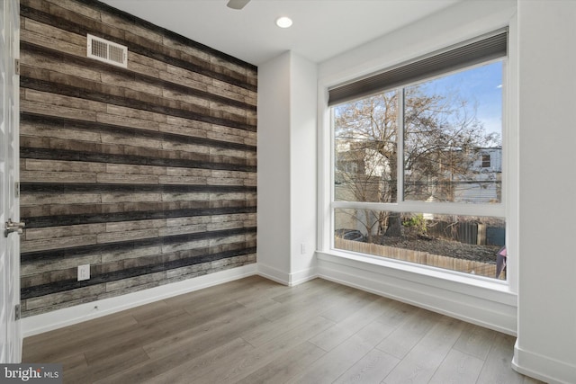 unfurnished room with wood walls and hardwood / wood-style flooring