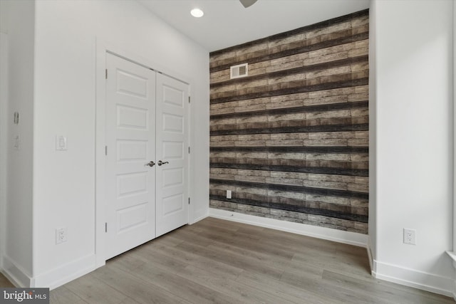 unfurnished bedroom with wooden walls, a closet, and hardwood / wood-style flooring