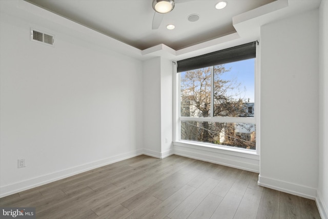 spare room featuring ceiling fan, wood-type flooring, and a tray ceiling