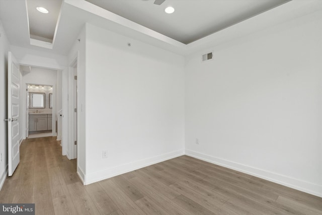 unfurnished room featuring a tray ceiling and light hardwood / wood-style floors