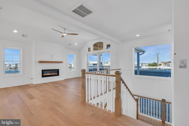 living room featuring vaulted ceiling with beams, a fireplace, ceiling fan, and light wood-type flooring