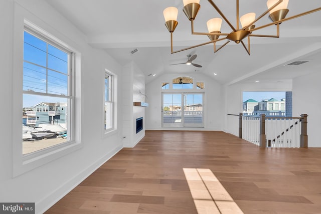 unfurnished living room featuring hardwood / wood-style flooring, a large fireplace, lofted ceiling, and ceiling fan with notable chandelier