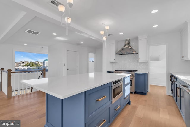 kitchen featuring blue cabinets, custom exhaust hood, appliances with stainless steel finishes, pendant lighting, and white cabinets