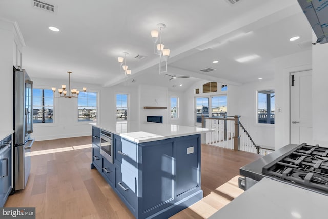 kitchen featuring appliances with stainless steel finishes, light hardwood / wood-style floors, hanging light fixtures, and a kitchen island