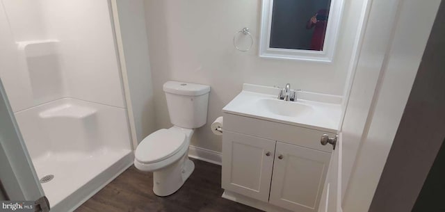 bathroom featuring hardwood / wood-style flooring, vanity, toilet, and a shower