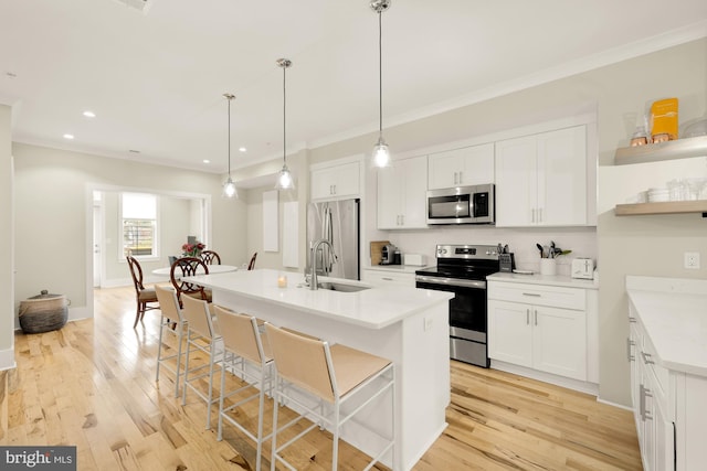 kitchen with a breakfast bar area, white cabinets, stainless steel appliances, and decorative light fixtures