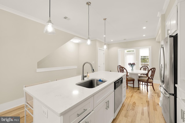 kitchen with white cabinetry, sink, stainless steel appliances, an island with sink, and decorative light fixtures