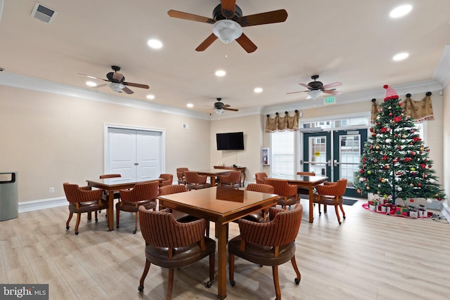 dining area featuring light wood-type flooring, crown molding, and french doors