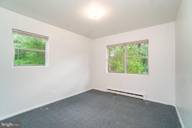 spare room featuring dark carpet and baseboard heating