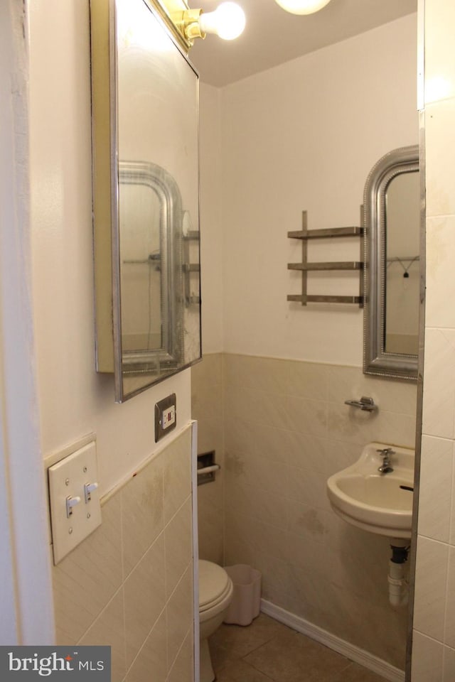 bathroom with tile patterned floors, toilet, sink, and tile walls