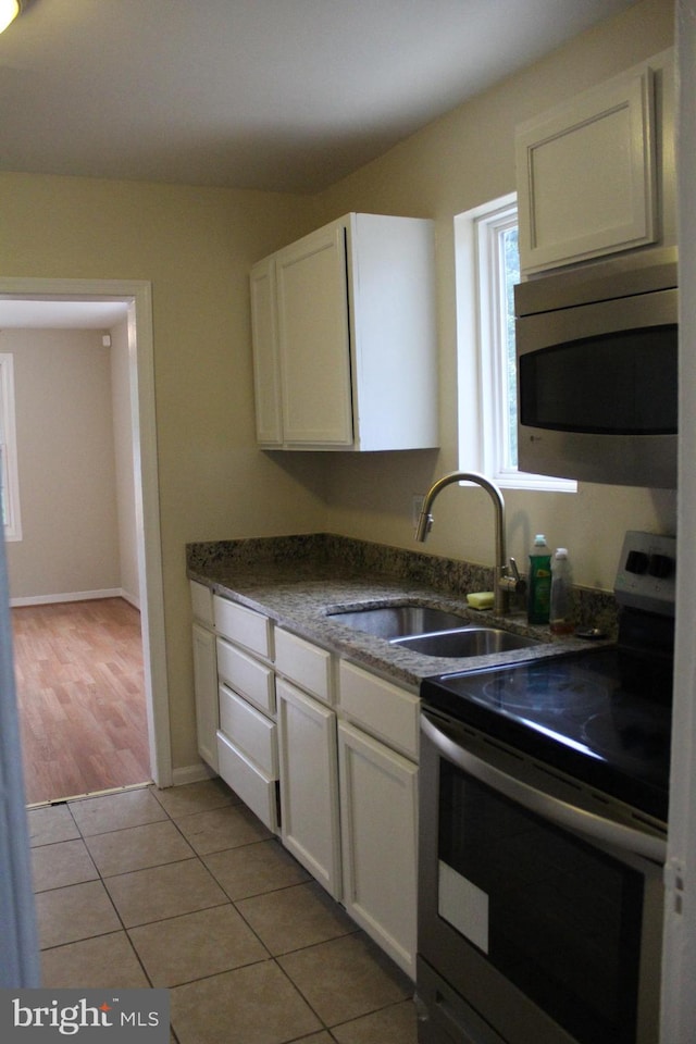 kitchen featuring light tile patterned flooring, white cabinetry, sink, and appliances with stainless steel finishes