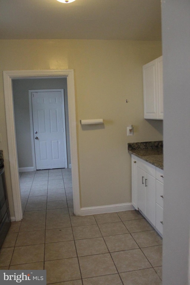 kitchen with dark stone countertops, white cabinetry, and light tile patterned flooring