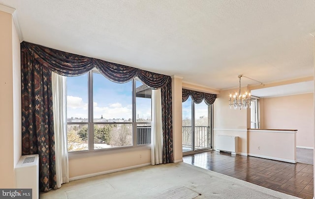 spare room with radiator heating unit, a textured ceiling, parquet floors, and a chandelier