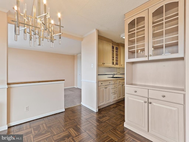 kitchen featuring backsplash, a textured ceiling, sink, cream cabinets, and decorative light fixtures