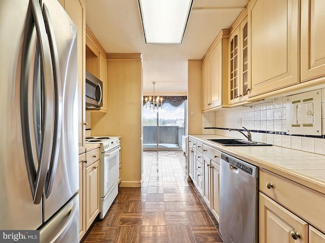 kitchen with stainless steel appliances, sink, pendant lighting, tile countertops, and a chandelier