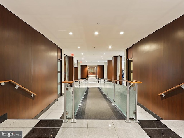 hall with light tile patterned floors and wooden walls