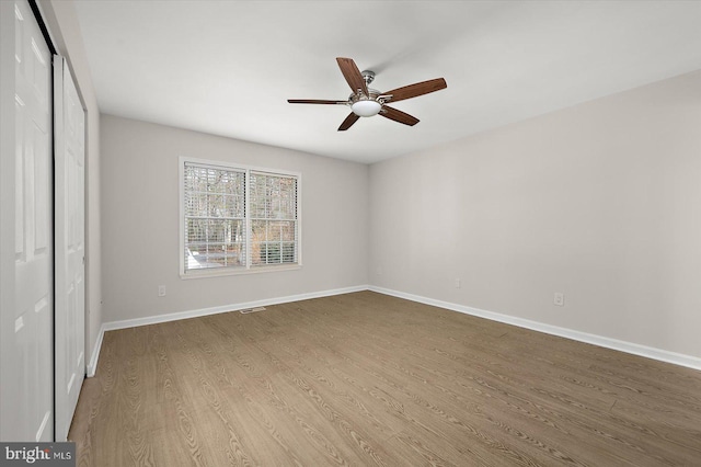 unfurnished bedroom featuring baseboards, visible vents, ceiling fan, wood finished floors, and a closet