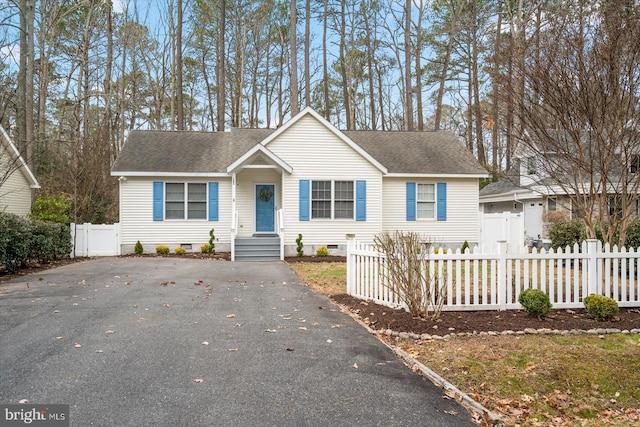 ranch-style home with crawl space, a fenced front yard, aphalt driveway, and roof with shingles