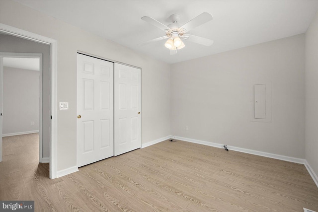 unfurnished bedroom with light wood-type flooring, a ceiling fan, baseboards, and a closet