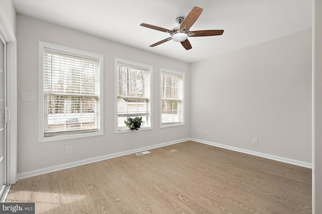 spare room with light wood-type flooring, visible vents, ceiling fan, and baseboards